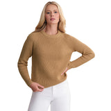 A woman modeling a ribbed knit long-sleeve sweater in camel tan, paired with white pants, against a plain white background.