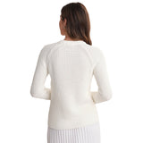 A woman shown from the back wearing a chalk-colored ribbed knit sweater and a white pleated skirt against a plain white background.