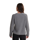 A woman viewed from the back wearing a gray ribbed knit sweater and dark jeans against a plain white background.