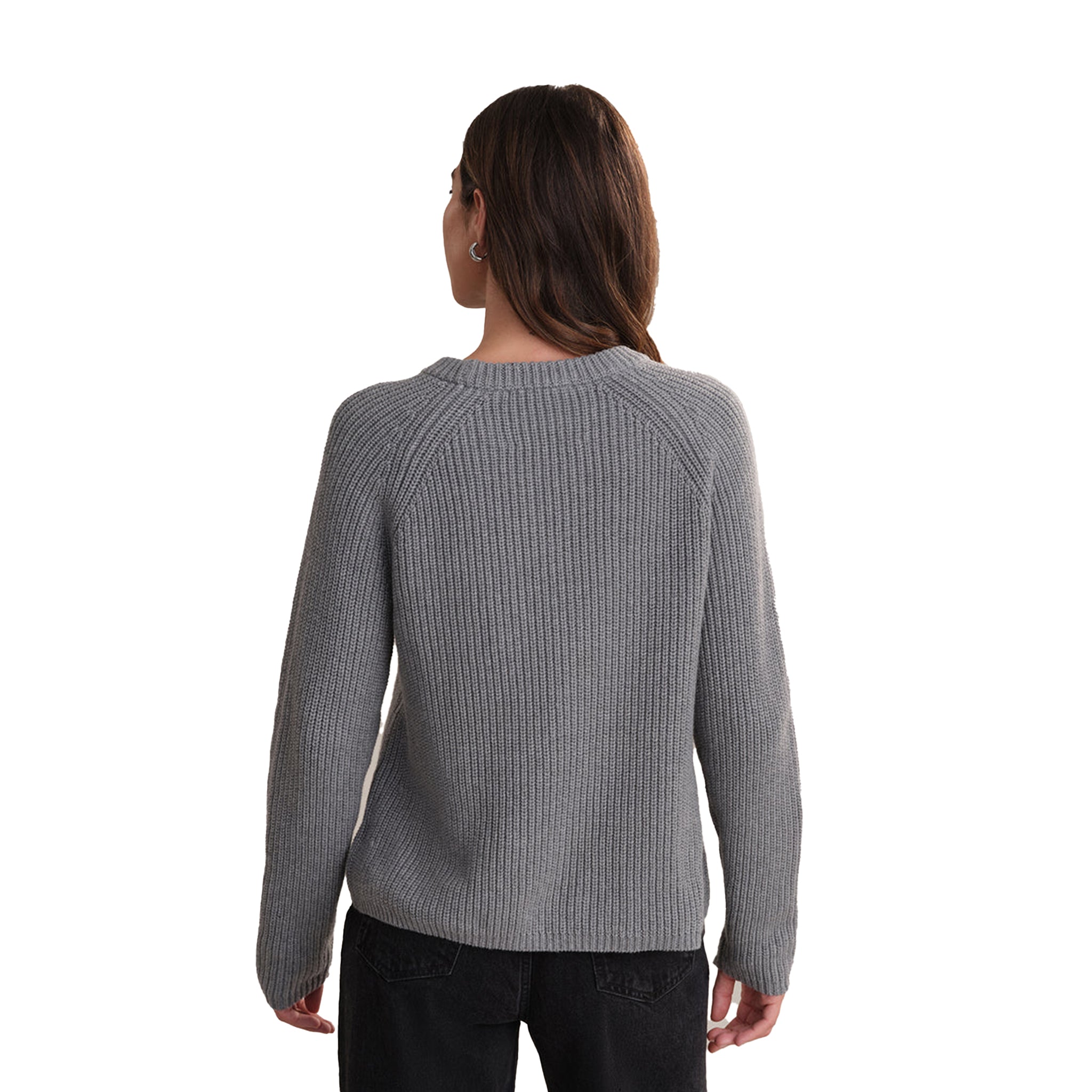 A woman viewed from the back wearing a gray ribbed knit sweater and dark jeans against a plain white background.