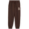 A pair of dark brown sweatpants with an elastic drawstring waist and side pockets, featuring a beige block letter 'D' on the left thigh, shown against a plain white background.