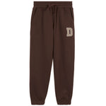 A pair of dark brown sweatpants with an elastic drawstring waist and side pockets, featuring a beige block letter 'D' on the left thigh, shown against a plain white background.