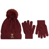 A winter accessory set featuring a cable-knit beanie with a fluffy pom-pom, a pair of matching knit gloves, and a small embroidered teddy bear logo on the beanie cuff, shown on a plain white background.