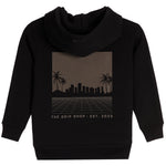 A black pullover hoodie with a rectangular graphic print on the chest. The graphic features a dark brown gradient background with a black silhouette of a city skyline, palm trees, and a grid pattern, with the text 'THE DRIP SHOP • EST. 2023