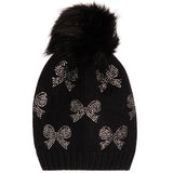 A black knit beanie hat featuring a large black faux fur pom-pom on top and silver rhinestone bow patterns knitted all over the front, shown against a plain white background.