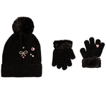 A black knit beanie with a fluffy pom-pom and decorative rhinestone bow embellishments, shown alongside matching black gloves with faux-fur trim on a plain white background.