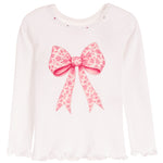 A white long-sleeve top with a large pink floral bow graphic on the front, small rhinestone embellishments around the neckline, and ruffled trim at the hem.