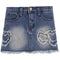 A blue denim mini skirt with a frayed hem, featuring distressed heart-shaped patches embellished with rhinestones on the front left and right sides.