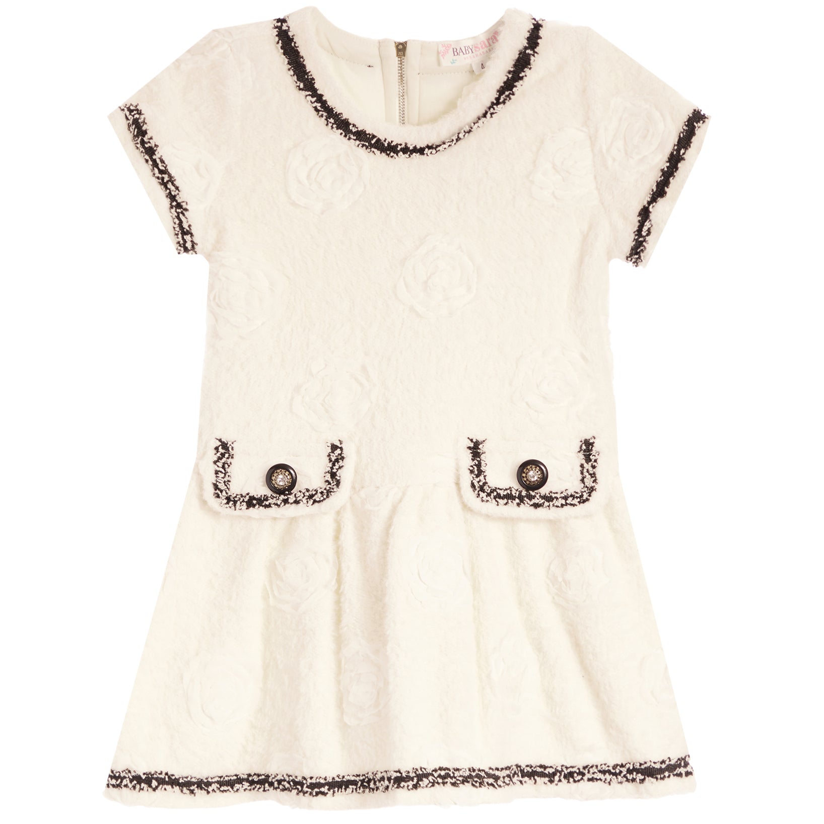 An off-white textured tweed dress with black and white fringed trim, featuring short sleeves, a round neckline, and two decorative patch pockets with button details.