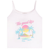 A white spaghetti-strap camisole tank top featuring a retro-style tropical graphic with palm trees, a pink and yellow sunset, and the text 'the good life' in pink script across the chest.
