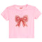 A light pink short-sleeve crop top featuring a large, decorative pearl-embellished bow on the front, displayed against a solid white background.