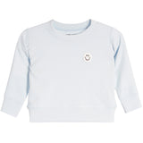 A light blue long-sleeve crewneck sweatshirt for a baby or toddler, featuring a small embroidered smiley face patch on the left chest.