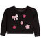 A black long-sleeve sweatshirt for toddlers, featuring pink and white applique patches including a bow, hearts, smiley faces, and a star on the front.