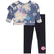 A toddler girl's two-piece outfit set featuring a blue and white tie-dye long-sleeve top with a glittery smiley face tic-tac-toe game, paired with black leggings that have a pink smiley face on the ankle.