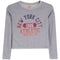 A heather gray long-sleeve crop top featuring a distressed graphic print on the front with the text 'NEW YORK CITY 1986 ATHLETIC BROOKLYN' in navy and coral colors.