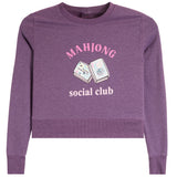 A heather purple cropped crewneck sweatshirt featuring a pink and white graphic print on the front with the text 'MAHJONG social club' and an illustration of mahjong tiles.