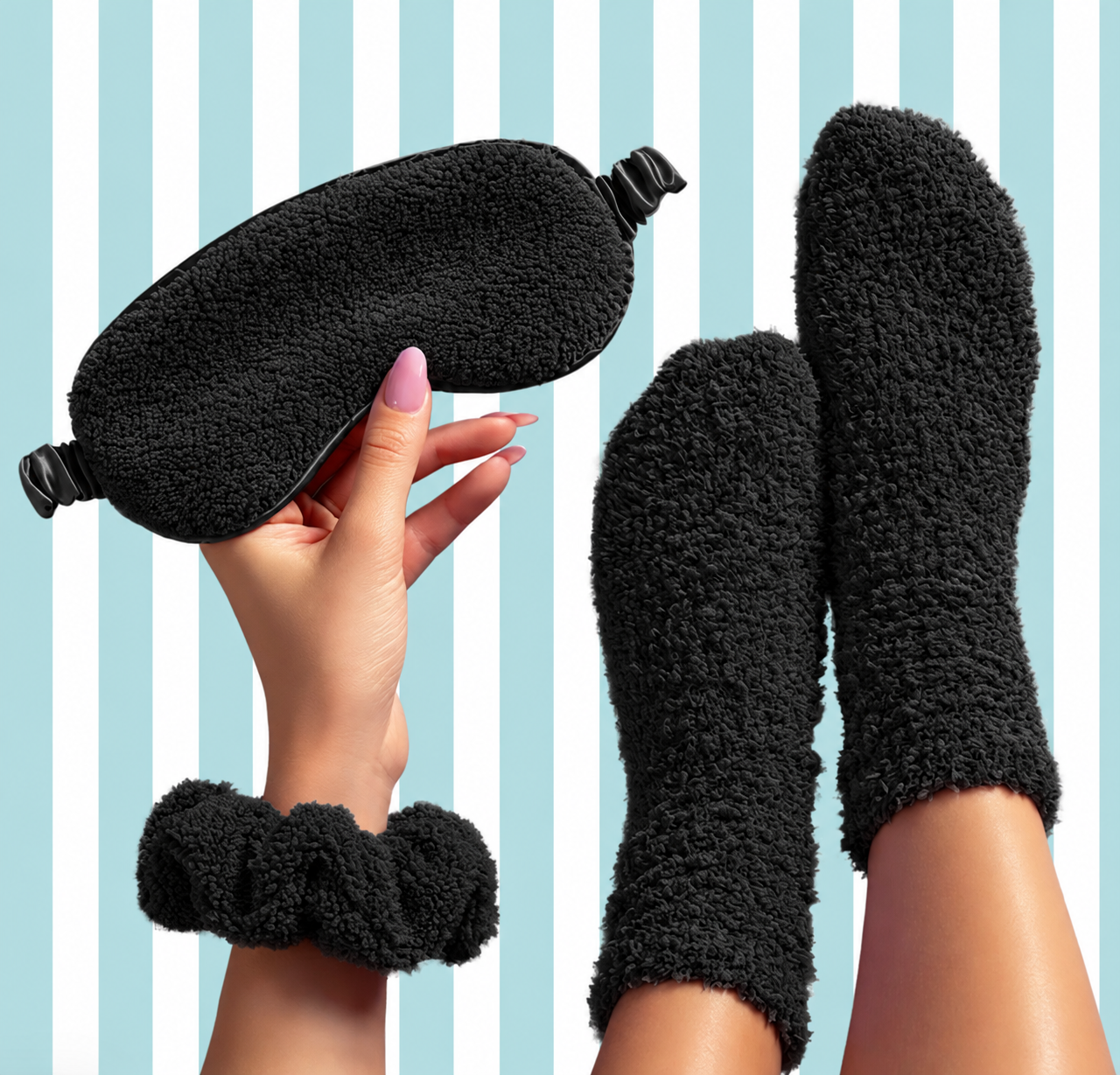 A cozy black fleece sleep set featuring a plush eye mask, matching scrunchie wristband, and fuzzy socks, shown on a person's hand and feet against a light blue and white striped background.