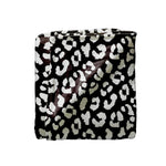 A folded blanket featuring a black and white leopard print pattern, shown against a plain white background.