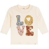 A cream-colored long-sleeve baby t-shirt featuring a colorful 'LOVE' graphic on the front, where each letter is filled with a different floral pattern in blue, yellow, pink, and brown.