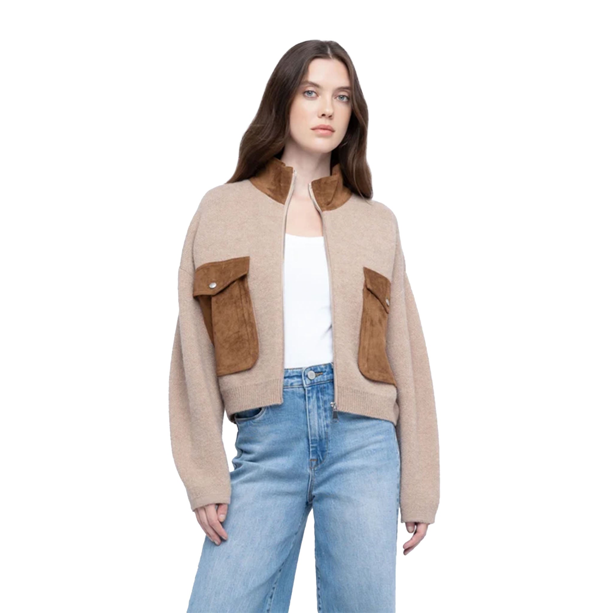 A woman modeling a cropped beige knit cardigan with brown suede-like flap pockets and a brown collar, worn over a white top and blue jeans against a plain white background.