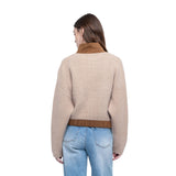 A woman shown from the back wearing a beige knit sweater with brown contrast trim at the collar and hem, paired with light blue jeans, against a plain white background.