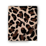 A folded blanket, featuring a classic leopard print pattern in beige, brown, and black, with one corner folded over on a white background.
