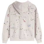 A light beige hooded sweatshirt shown from the back, featuring a colorful paint splatter pattern in red, green, blue, and gray.