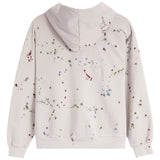 A light beige hooded sweatshirt shown from the back, featuring a colorful paint splatter pattern in red, green, blue, and gray.
