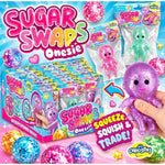 Sugar Swaps Onesie CurioStix surprise toy box display with multiple packaged and loose glitter babies, plus a hand holding a purple glitter octopus on a bright blue promotional background.
