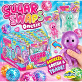 Sugar Swaps Onesie CurioStix surprise toy box display with multiple packaged and loose glitter babies, plus a hand holding a purple glitter octopus on a bright blue promotional background.
