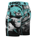 A pair of men's boxer briefs featuring a graphic print of a teal bear, surrounded by falling dollar bills. The waistband is teal with black 'PSD' lettering and circular logos.