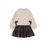 A children's long-sleeve dress with a cream-colored knit top and a black tiered tulle skirt with small bow details, shown on a plain white background.