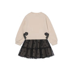 A children's long-sleeve dress shown from the back, featuring a beige sweatshirt-style upper body with black ribbon accents at the waist and a black tulle tutu skirt with small black bow details.
