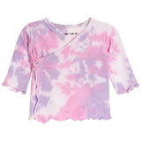 A baby girl's long-sleeve wrap top featuring a pink and purple tie-dye pattern, a crossover front, and a snap button closure on the left side. The shirt has a scalloped edge on the sleeves and bottom hem, shown against a plain white background.