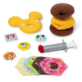 A children's toy play set featuring plush donut-shaped cushions, a yellow Mickey Mouse-shaped cushion, a gray syringe with a red plunger, and several colorful donut-shaped pieces with character faces, arranged on a white background.