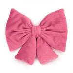 A large plush pink bow with a soft velvety texture, photographed against a clean white background.