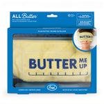 A boxed plush butter scarf from Fred, shown in its retail packaging. The product is a pale yellow towel-style scarf with 'BUTTER ME UP' embroidered in dark blue across the front.