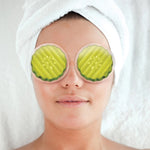 Person wearing pickle slices over their eyes with a towel on their head, against a white background
