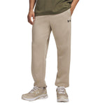 A person wearing beige Under Armour jogger sweatpants, an olive green t-shirt, and beige running shoes, shown from the waist down on a white background.