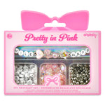 A pink DIY bracelet set in retail packaging with a bow-shaped hanger tab. The package contains three compartments with beads and charms pastel beads, and silver beads.