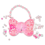 A pink glittery bow-shaped charm bag with a beaded strap, surrounded by scattered decorative pink and silver beads, star-shaped embellishments, and ribbon pieces on a white background.