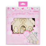 Popcorn Gingerbread House DIY craft kit in its original pink packaging, showing the wooden house pieces and tools visible through a clear window.