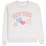 A light heather gray crewneck sweatshirt featuring a 'NEW YORK' graphic in pink outlined letters, decorated with a light blue heart, a pink heart, and two pink-outlined stars on the front.