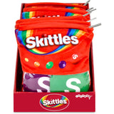 A retail display box filled with red plush pouches designed to look like Skittles candy bags, with visible metal zipper pulls and multiple Skittles branding panels on the front.