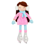 A plush doll with long brown hair, white earmuffs, a pink dress, a light blue scarf, blue gloves, and gray roller skates, shown against a plain white background.