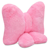 A pink plush bow-shaped pillow with a soft, fuzzy texture, shown against a plain white background.