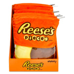 A display box filled with plush Reese's Pieces candy bags in orange, with one front bag showing yellow and brown candy-filled sections and silver zipper pulls visible.