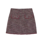 A tweed mini skirt in a marled burgundy and gray pattern, featuring two decorative front pockets with matching embroidered detailing, shown flat on a white background.