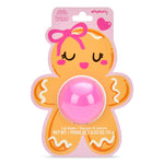 A packaged lip balm shaped like a smiling gingerbread cookie, with a pink oval balm container in the center and a card backing showing vanilla scent text and a pink heart logo.
