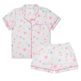 A two-piece children's pajama set featuring a short-sleeve button-front top and matching shorts in white, decorated with a pastel star pattern in pink, blue, and yellow, finished with pink piping trim.